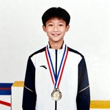 青少年学员小陈头像照片，一位约14岁的少年，穿着比赛服，脖子上挂着奖牌，站在领奖台旁露出腼腆的笑容。
